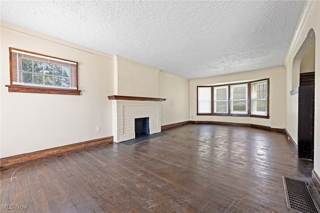 unfurnished living room with a brick fireplace, ornamental molding, a textured ceiling, and dark hardwood / wood-style flooring