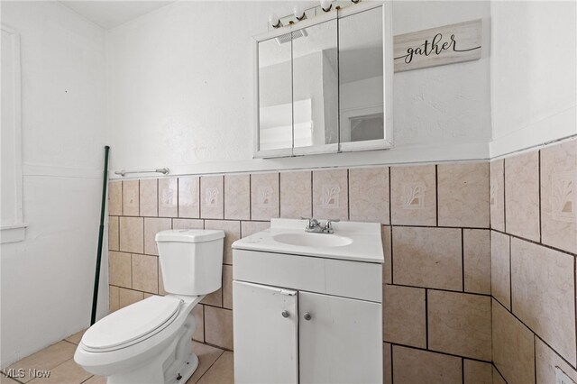 bathroom featuring backsplash, toilet, tile patterned flooring, vanity, and tile walls