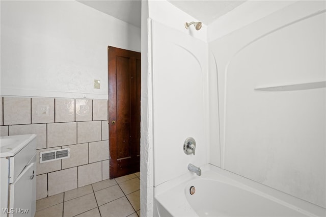 bathroom with washtub / shower combination, vanity, tile patterned flooring, and tile walls