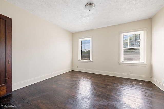 unfurnished room with a textured ceiling, dark wood-type flooring, and a healthy amount of sunlight