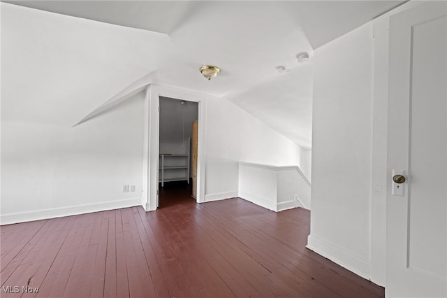 bonus room with baseboards, vaulted ceiling, and dark wood-type flooring