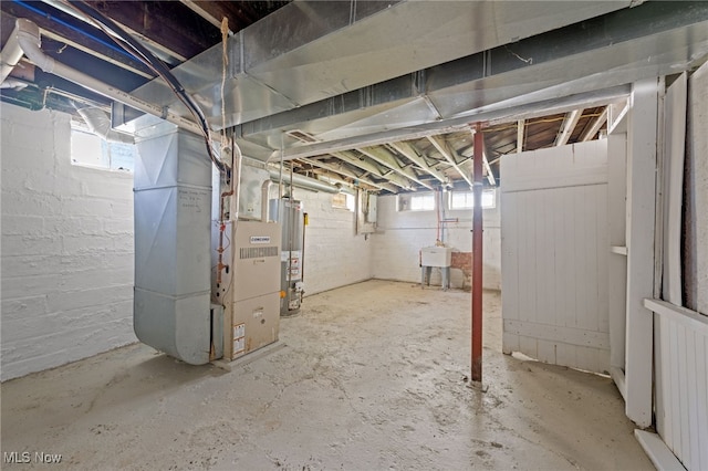 basement featuring heating unit, water heater, and a sink