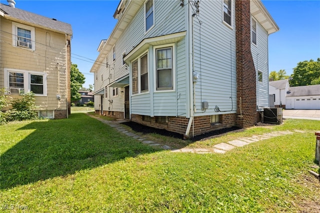 view of side of home featuring a garage, a lawn, and central AC