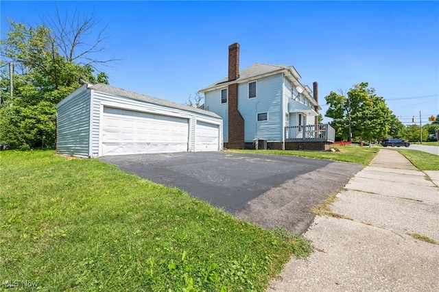 view of side of property with a garage, a yard, a chimney, and an outbuilding