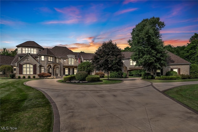 french country style house featuring a balcony, stone siding, curved driveway, and a front yard