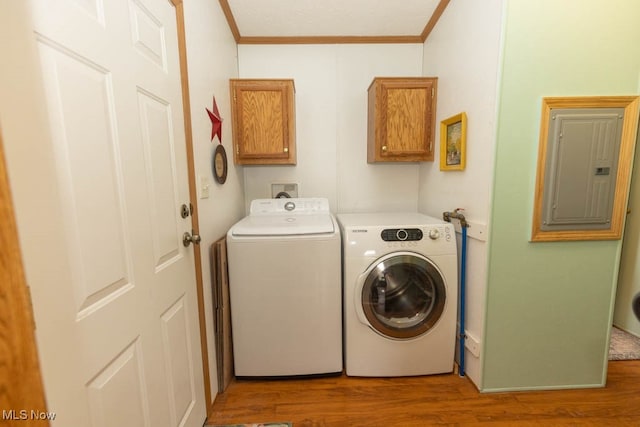 laundry area featuring crown molding, light hardwood / wood-style flooring, electric panel, cabinets, and washing machine and dryer