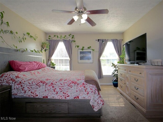 bedroom featuring ceiling fan, light carpet, and a textured ceiling