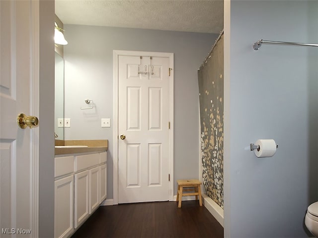 bathroom featuring hardwood / wood-style floors, a textured ceiling, vanity, curtained shower, and toilet