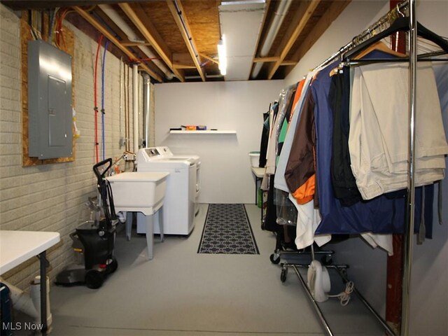 clothes washing area with brick wall, independent washer and dryer, and electric panel