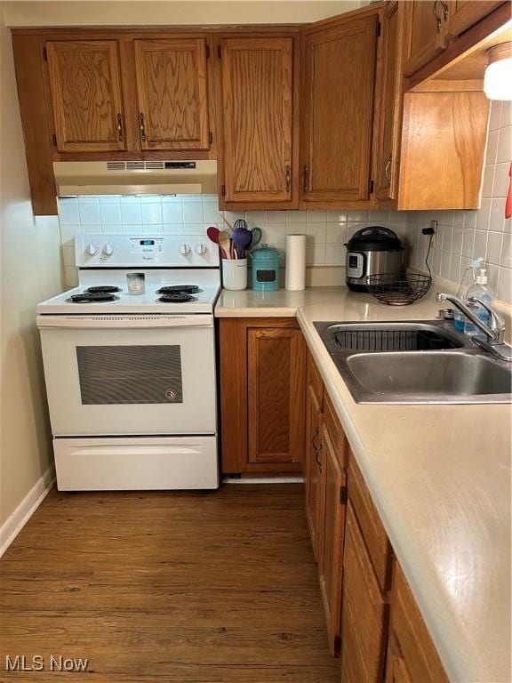 kitchen featuring white range with electric cooktop, a sink, light countertops, under cabinet range hood, and tasteful backsplash