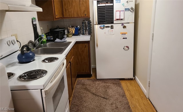 kitchen featuring sink, decorative backsplash, white appliances, and premium range hood