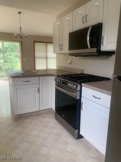 kitchen featuring appliances with stainless steel finishes, decorative light fixtures, white cabinetry, a notable chandelier, and light tile patterned flooring