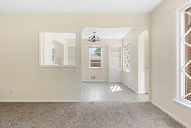 carpeted foyer entrance with a notable chandelier