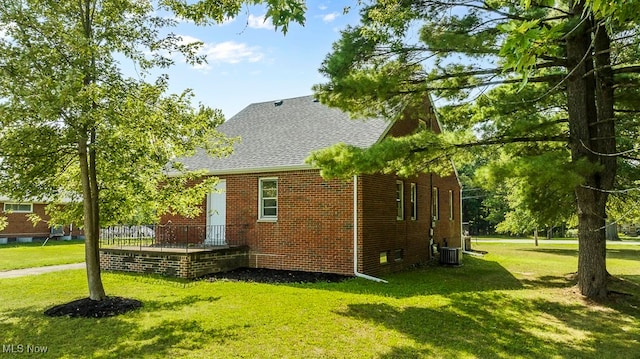 view of side of property featuring cooling unit and a yard