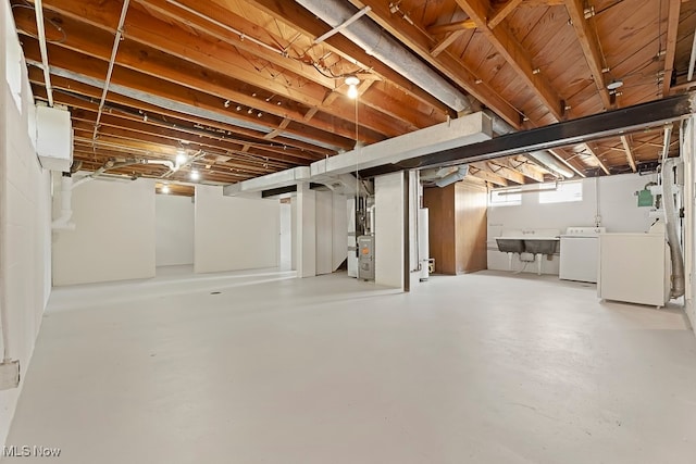 basement featuring washing machine and clothes dryer, heating unit, and sink