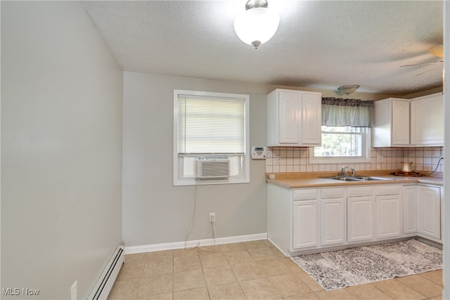 kitchen featuring white cabinets, a baseboard heating unit, sink, decorative backsplash, and a textured ceiling