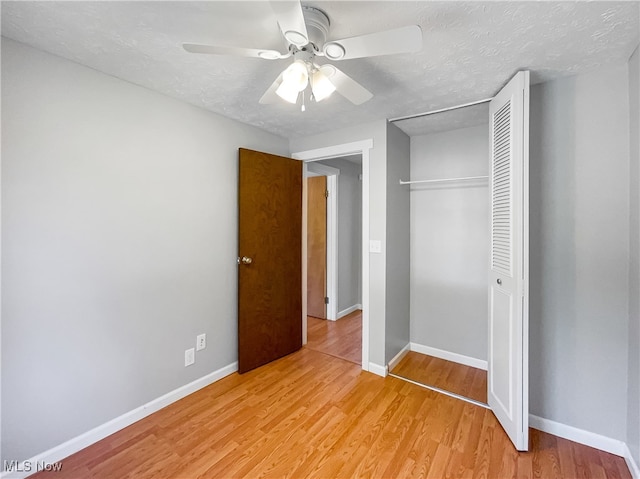 unfurnished bedroom featuring a closet, a textured ceiling, ceiling fan, and light hardwood / wood-style floors