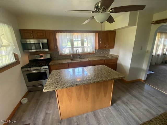 kitchen featuring brown cabinetry, tasteful backsplash, stainless steel appliances, and a sink