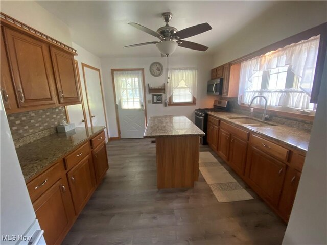 kitchen with dark hardwood / wood-style flooring, a kitchen island, sink, ceiling fan, and appliances with stainless steel finishes