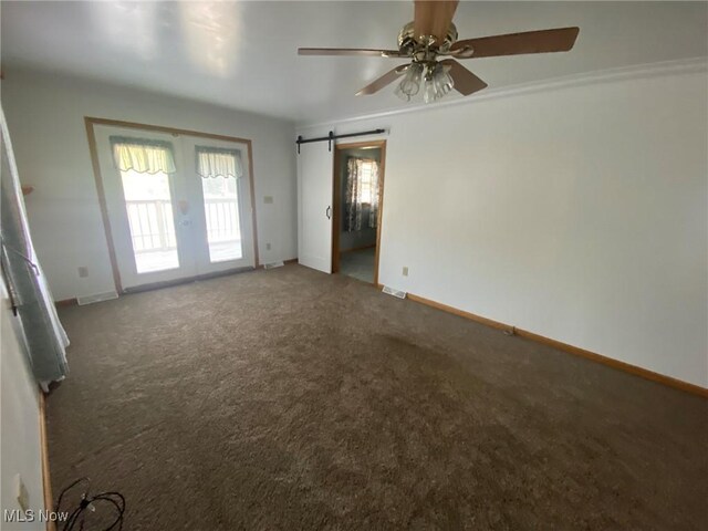 empty room featuring crown molding, french doors, a barn door, carpet, and ceiling fan