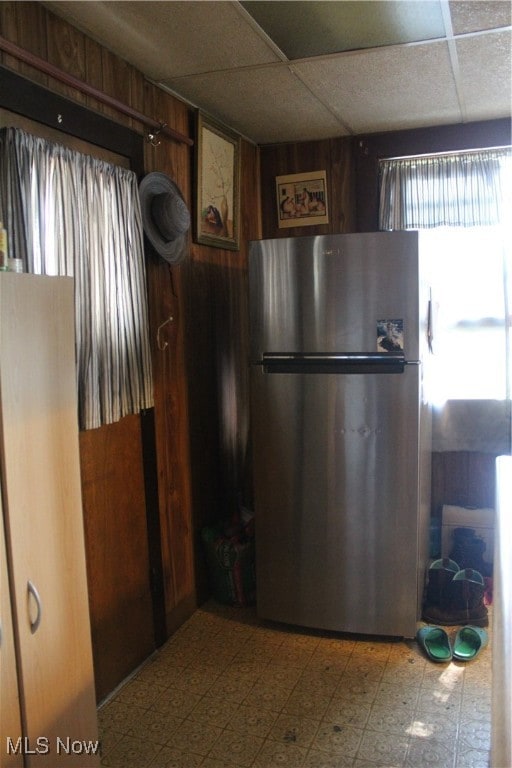 kitchen with a drop ceiling, tile patterned floors, and stainless steel refrigerator