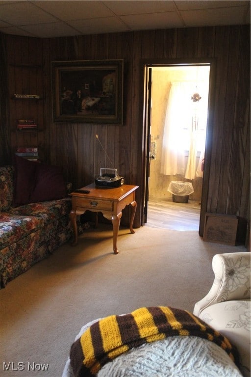 carpeted living room featuring a paneled ceiling and wooden walls