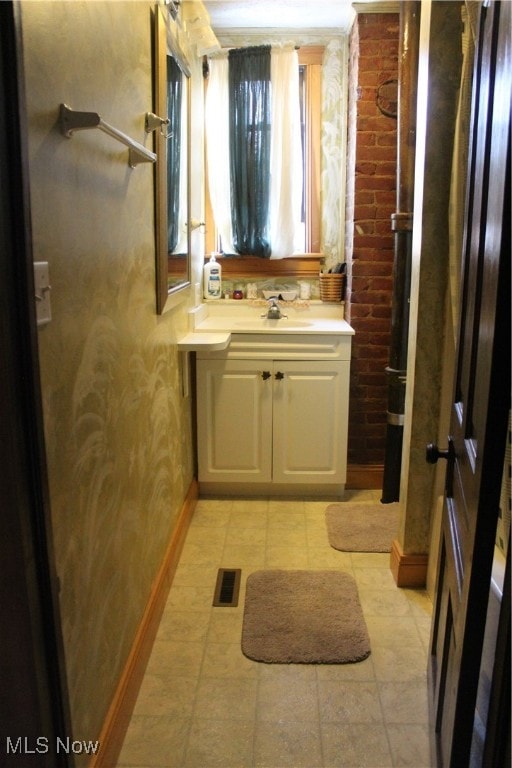 bathroom with tile patterned flooring, brick wall, and vanity