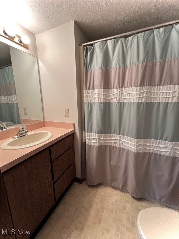 bathroom featuring vanity, toilet, a textured ceiling, and walk in shower