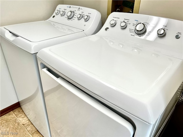 laundry area with washer and clothes dryer and light tile patterned flooring