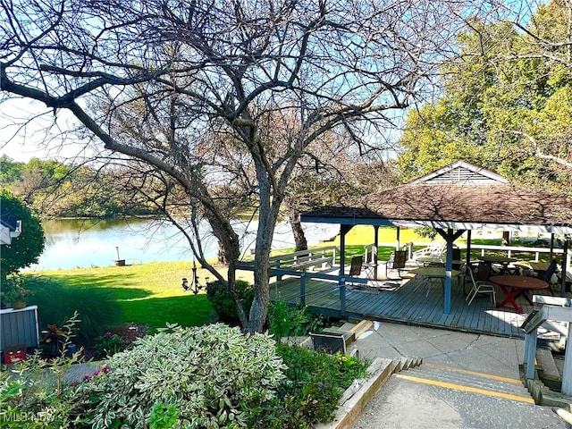 view of property's community featuring a gazebo, a deck with water view, and a yard