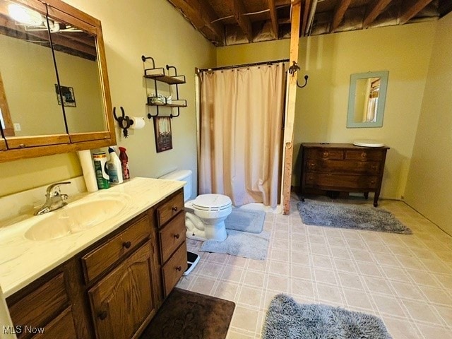 bathroom with toilet, beamed ceiling, tile patterned flooring, and vanity