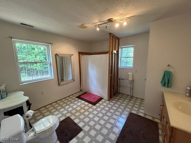 bathroom featuring rail lighting, vanity, tile patterned flooring, a textured ceiling, and toilet