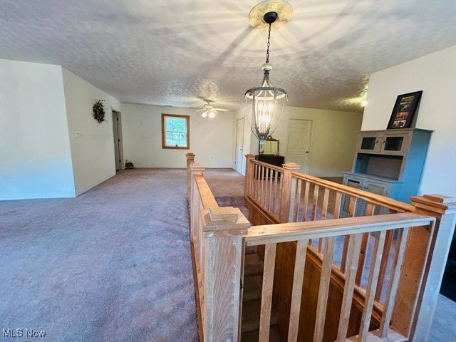 interior space featuring carpet floors, a textured ceiling, and ceiling fan