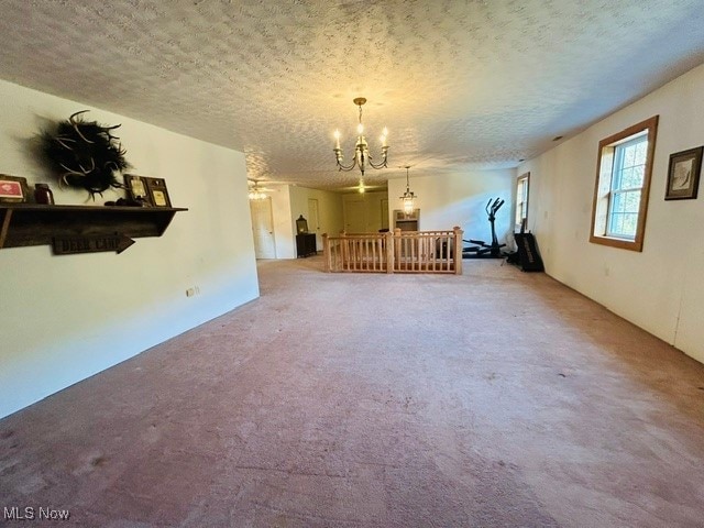 interior space featuring a textured ceiling, carpet flooring, and a chandelier