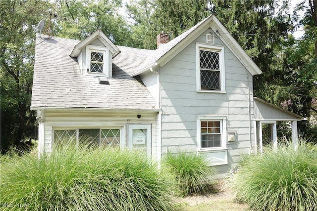 view of front of property featuring a garage, a shingled roof, and a chimney