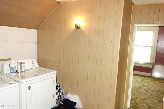 clothes washing area with laundry area, wooden walls, and washing machine and clothes dryer