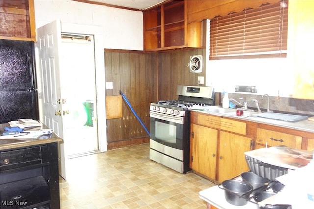 kitchen featuring light countertops, visible vents, a sink, wooden walls, and gas range