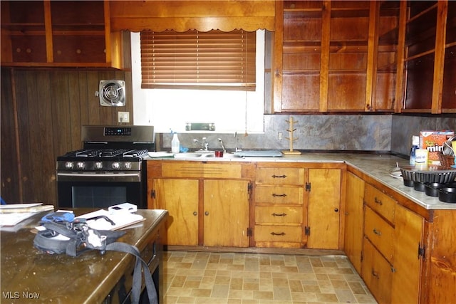 kitchen with visible vents, decorative backsplash, gas range, brown cabinets, and stone finish flooring