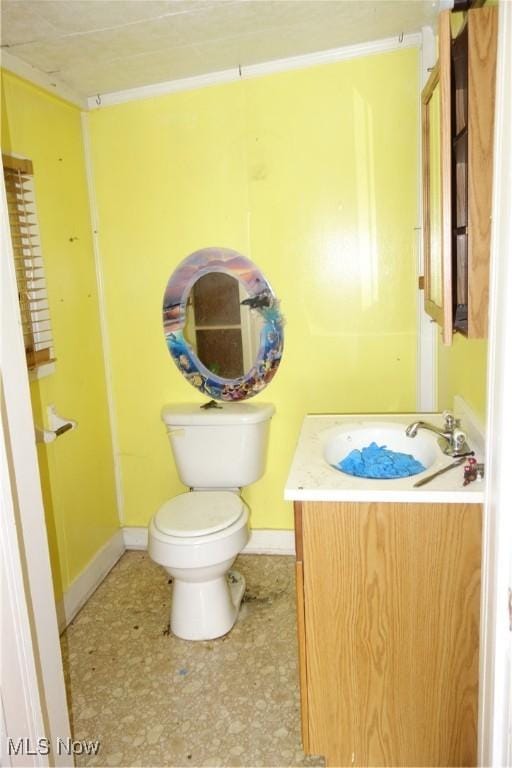 half bathroom featuring toilet, baseboards, and vanity