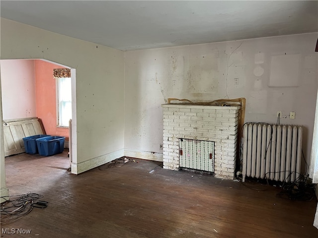 unfurnished living room with a fireplace, dark hardwood / wood-style floors, and radiator