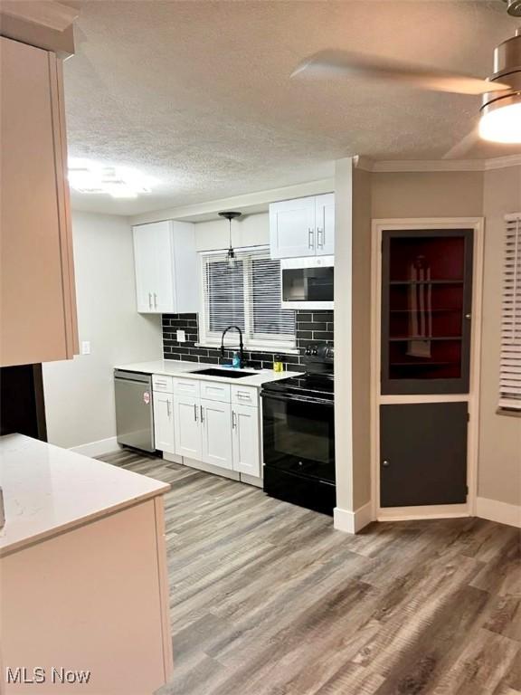 kitchen featuring stainless steel appliances, light hardwood / wood-style flooring, white cabinetry, tasteful backsplash, and sink