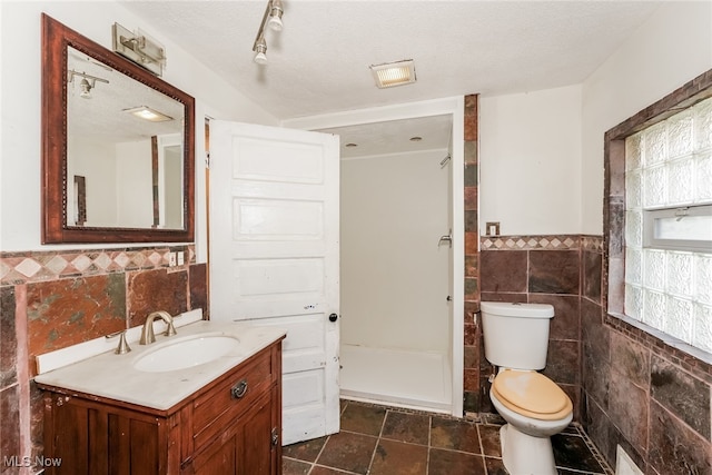 bathroom with vanity, toilet, tile patterned flooring, and tile walls