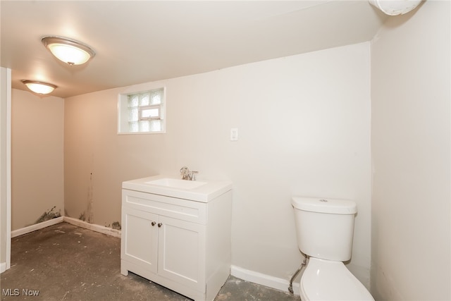 bathroom with toilet, concrete flooring, and vanity