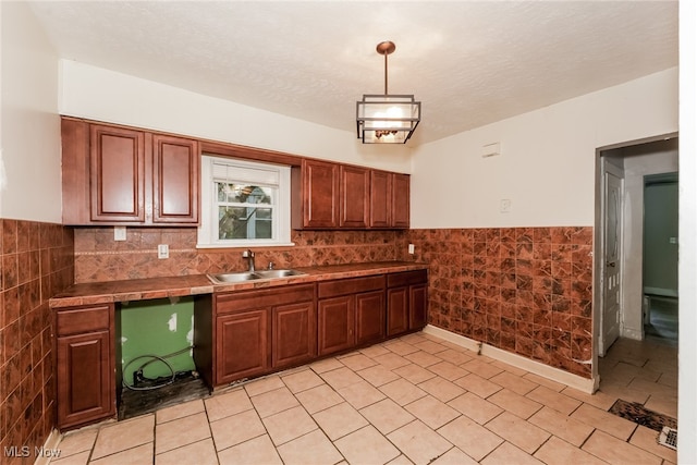 kitchen featuring tasteful backsplash, sink, a textured ceiling, light tile patterned floors, and hanging light fixtures