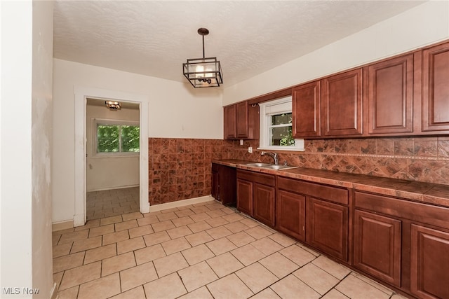 kitchen featuring decorative backsplash, sink, a textured ceiling, light tile patterned floors, and hanging light fixtures