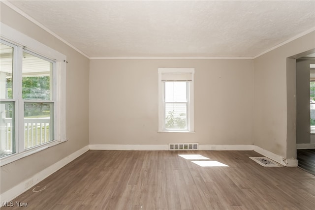 unfurnished room with plenty of natural light, ornamental molding, and hardwood / wood-style flooring