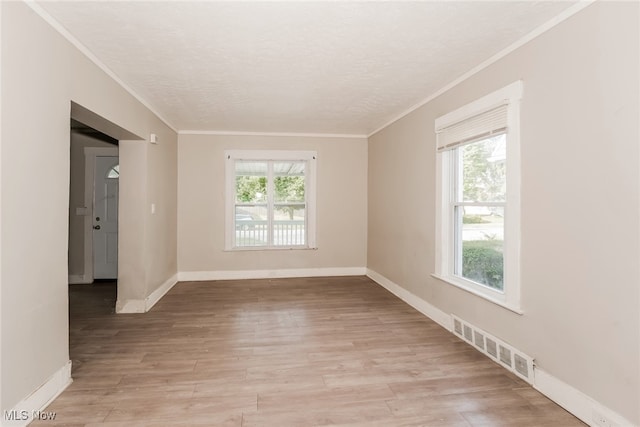 empty room featuring light hardwood / wood-style flooring and crown molding