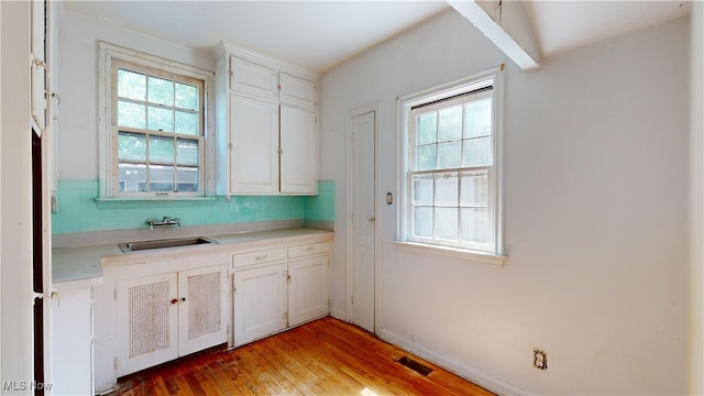 kitchen featuring sink, white cabinets, decorative backsplash, and wood-type flooring