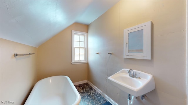 bathroom featuring sink, a bathing tub, and vaulted ceiling