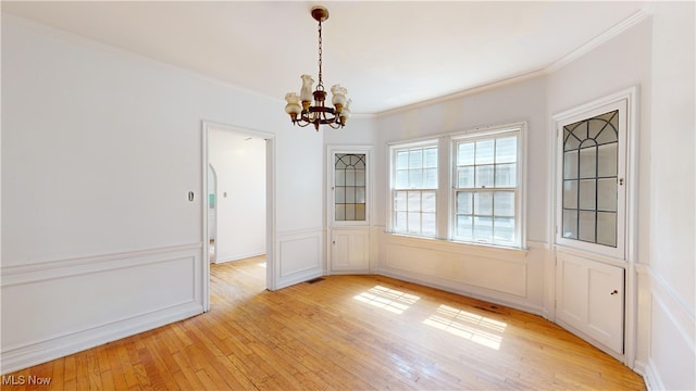 unfurnished dining area featuring light hardwood / wood-style flooring, a notable chandelier, and crown molding